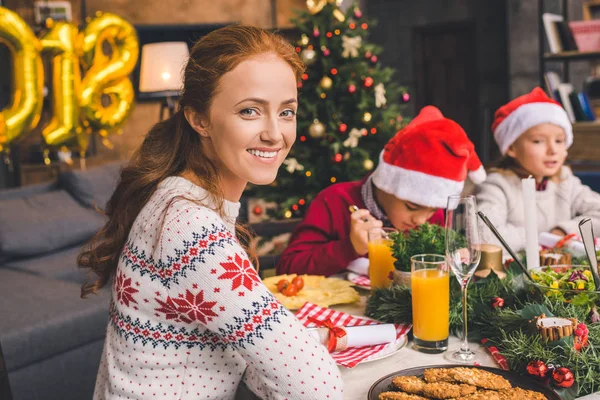 Mother sitting at christmas table with kids — Stock Photo