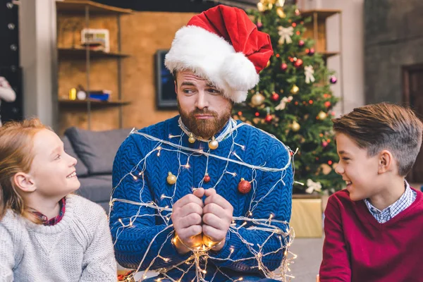 Kids and father tied up with garland — Stock Photo