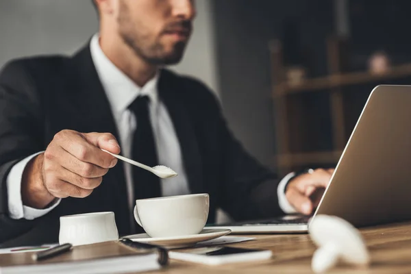 Empresario añadir azúcar al café — Stock Photo