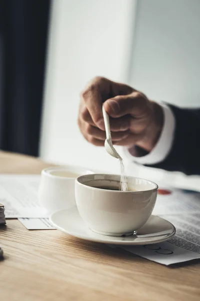 Empresário adicionando açúcar ao café — Fotografia de Stock