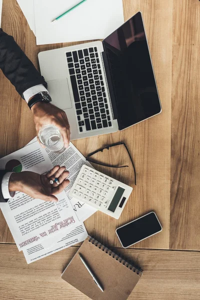 Empresario con pastillas en el lugar de trabajo — Stock Photo