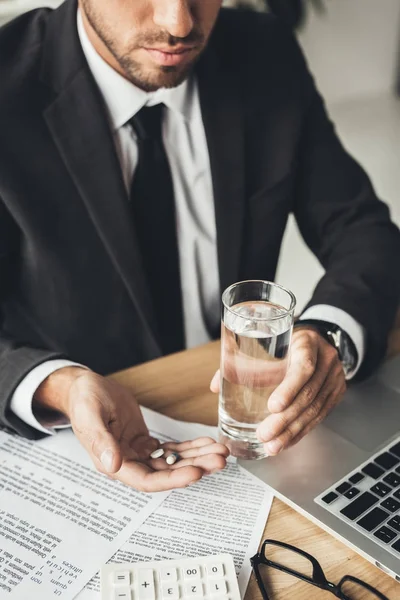 Hombre de negocios con pastillas y vaso de agua - foto de stock