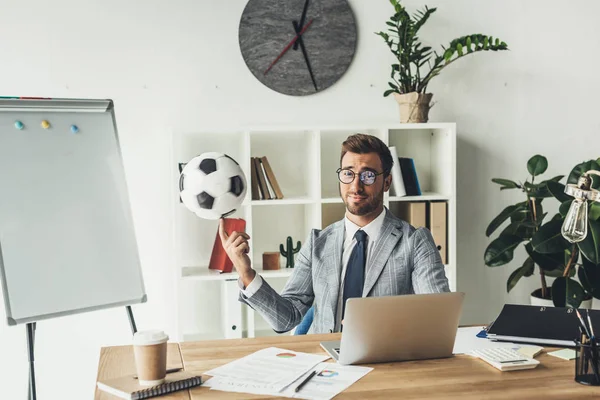 Businessman spinning soccer ball on finger — Stock Photo