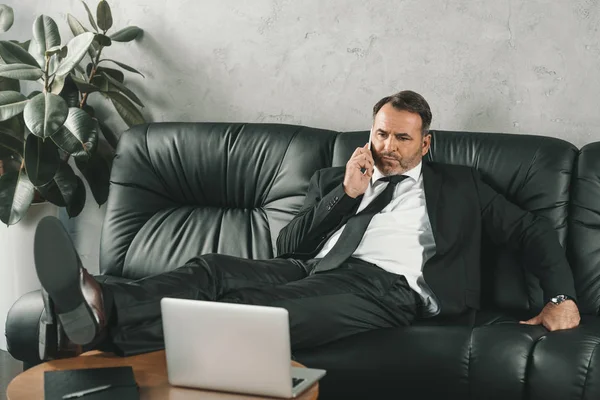 Businessman talking by phone on couch — Stock Photo