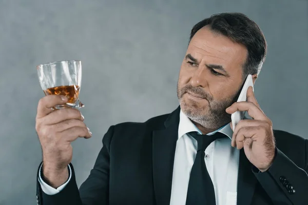 Uomo d'affari con bicchiere di whisky che parla per telefono — Foto stock