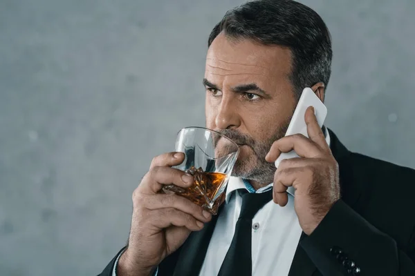 Businessman talking by phone with whiskey — Stock Photo
