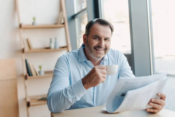 Businessman drinking coffee with newspaper — Stock Photo