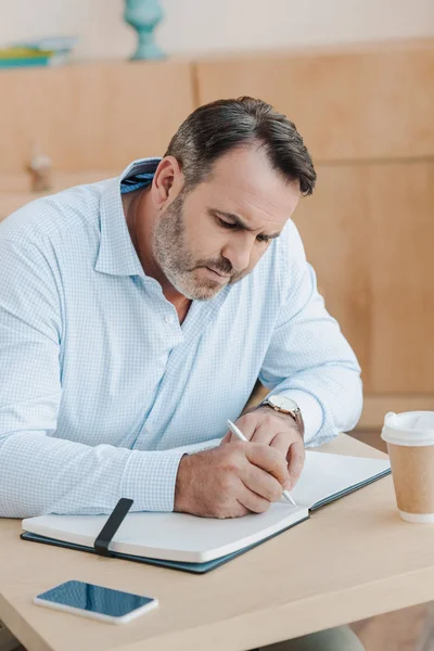 Geschäftsmann schreibt in Notizbuch — Stockfoto