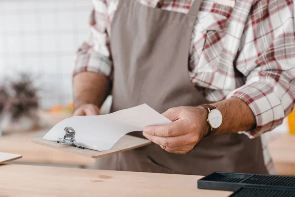 Bartender checking paper on clipboard — Stock Photo
