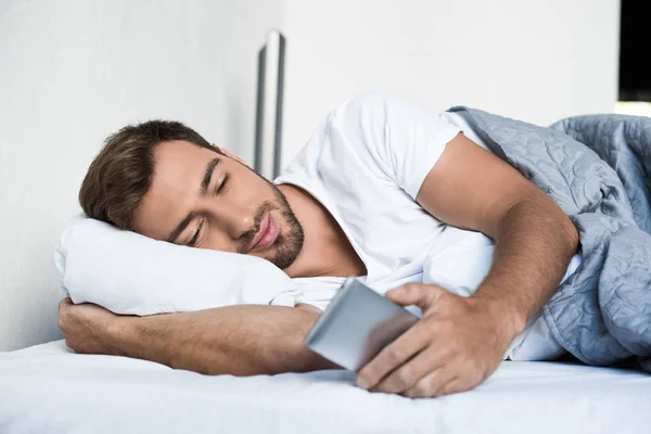 Людина використовує смартфон у ліжку — стокове фото