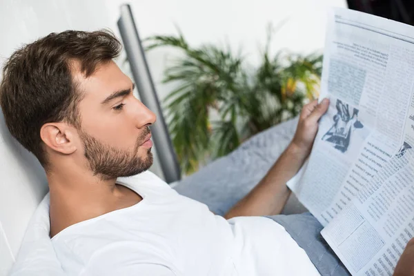 Homme au lit lisant le journal — Photo de stock