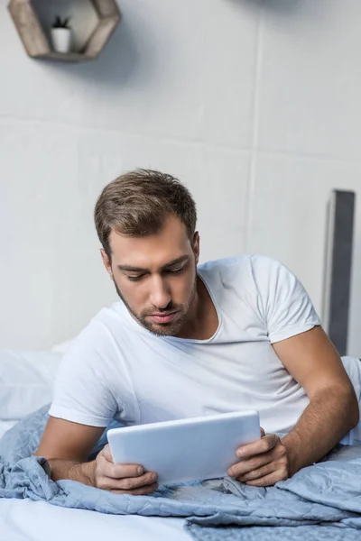 Людина в ліжку за допомогою цифрового планшета — стокове фото