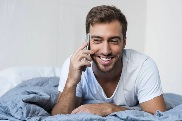 Hombre en la cama hablando por teléfono - foto de stock