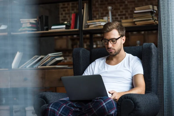 Man in armchair using laptop — Stock Photo