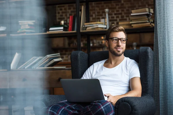 Homme dans le fauteuil utilisant un ordinateur portable — Photo de stock