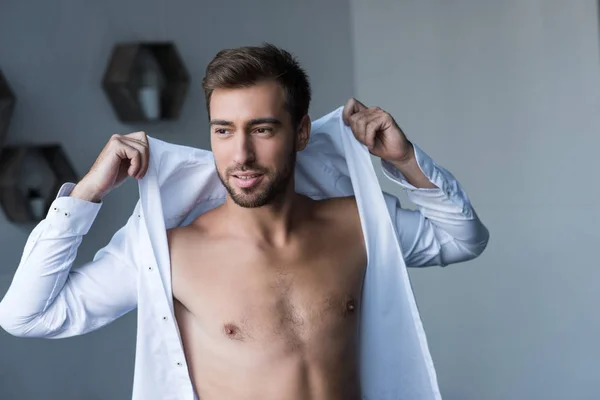 Man putting on shirt — Stock Photo