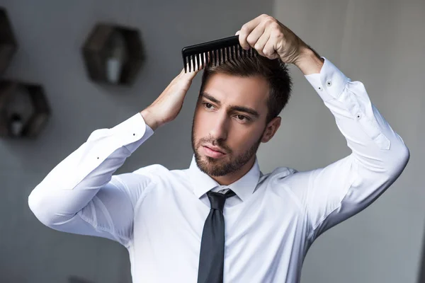 Businessman combing hair — Stock Photo