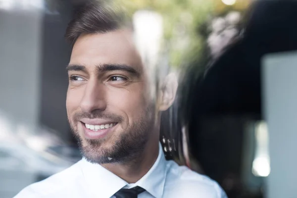 Un hombre de negocios sonriente mirando por la ventana - foto de stock