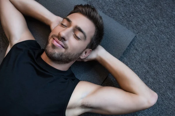 Homme sur tapis de yoga avec les yeux fermés — Photo de stock