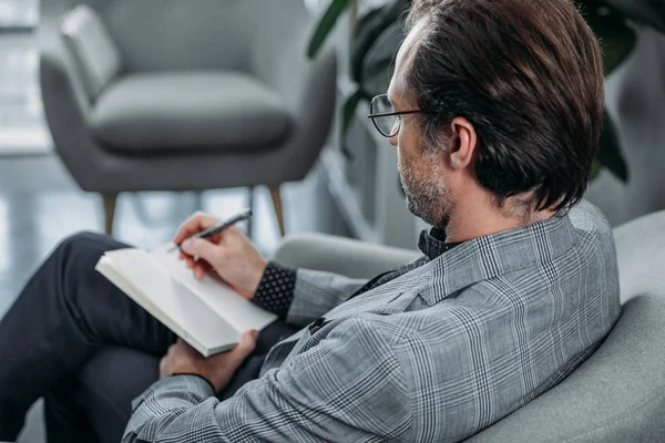 Homme d'affaires prenant des notes dans un carnet — Photo de stock