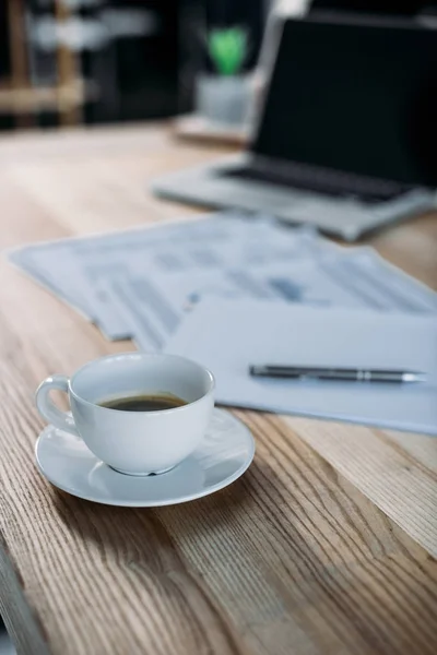 Cup of coffee and laptop on table — Stock Photo