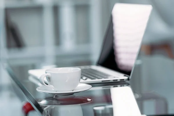 Cup of coffee and laptop on table — Stock Photo