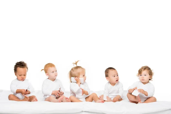 Niños pequeños multiculturales con smartphones - foto de stock