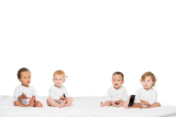 Niños pequeños multiculturales sosteniendo teléfonos inteligentes - foto de stock