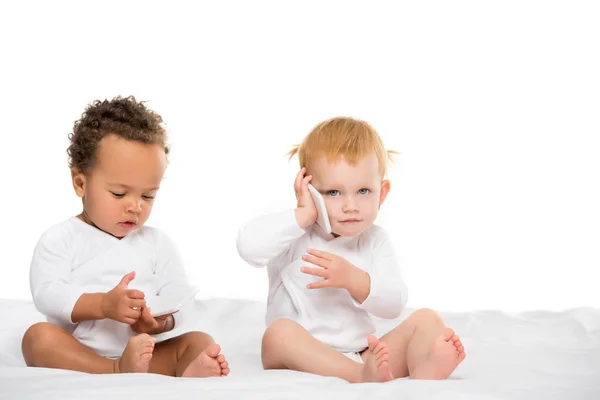 Niños pequeños multiculturales con teléfonos inteligentes digitales - foto de stock