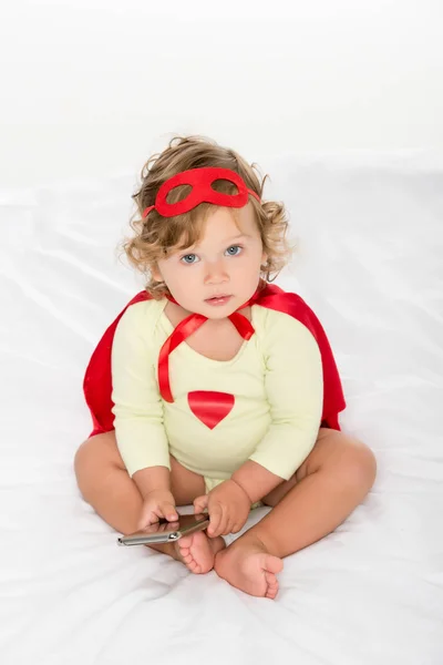 Niño pequeño en traje de superhéroe con teléfono inteligente — Stock Photo