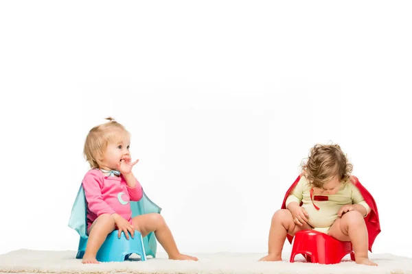 Niños pequeños sentados en macetas - foto de stock