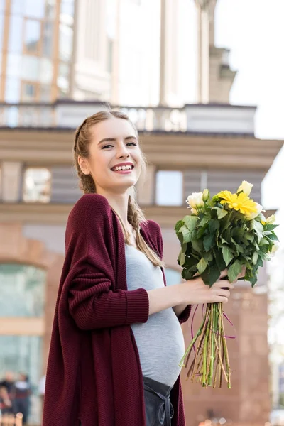 Femme enceinte avec bouquet de fleurs — Photo de stock