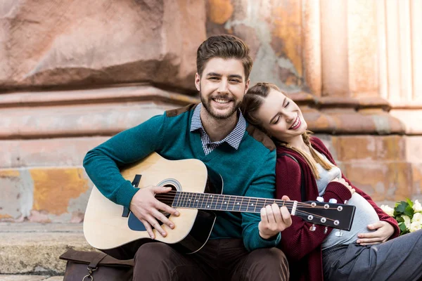 Homem tocando guitarra para esposa grávida — Fotografia de Stock