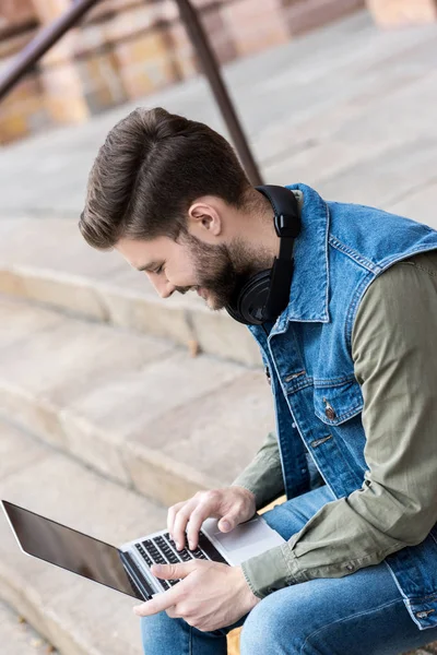 Man using laptop on street — Stock Photo