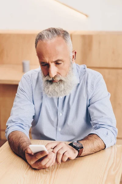 Hombre mayor con teléfono inteligente en la cafetería - foto de stock