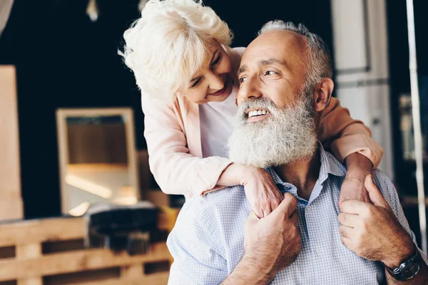 Elderly woman hugging husband in cafe — Stock Photo