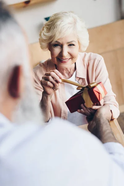 Seniorin packt Geschenk aus — Stockfoto