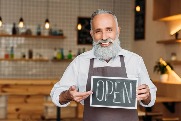 Senior worker holding open chalkboard — Stock Photo