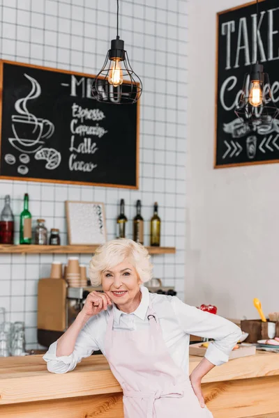 Smiling senior worker at counter — Stock Photo