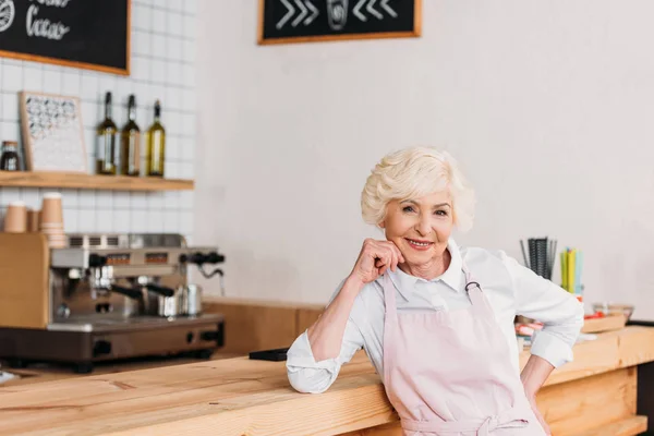 Smiling senior worker at counter — Stock Photo