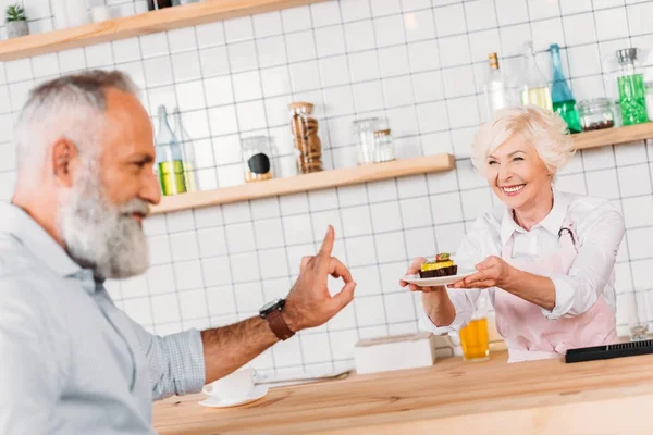 Cafe worker offering pastry to man — Stock Photo