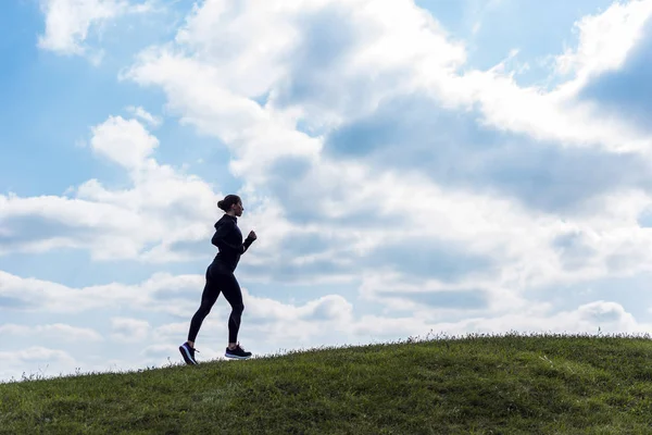 Mujer deportiva trotando en la colina - foto de stock