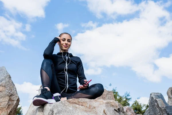 Mujer sentada en las rocas y escuchando música - foto de stock