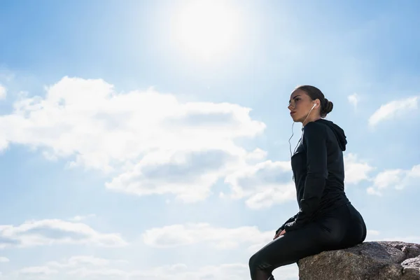 Sportliche Frau sitzt auf Felsen — Stockfoto