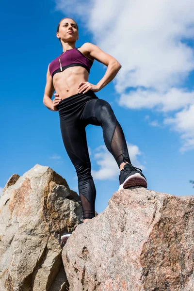 Sportliche Frau steht auf Felsen — Stockfoto
