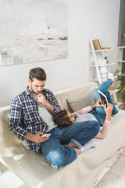 Couple sur canapé en utilisant des appareils — Photo de stock