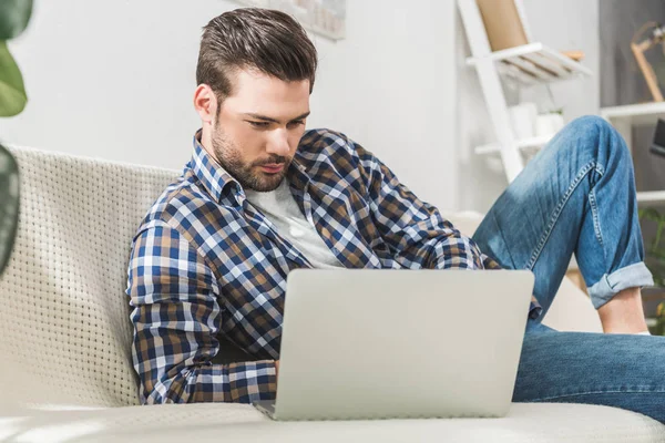 Uomo sul divano con computer portatile — Foto stock