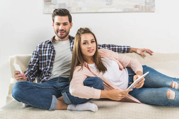 Couple sur canapé avec appareils — Photo de stock