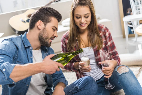 Casal no chão derramando champanhe — Fotografia de Stock