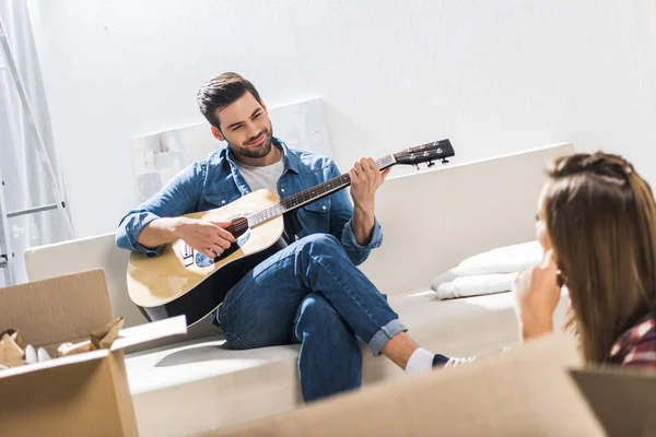 Junger Mann auf Sofa spielt Gitarre — Stockfoto